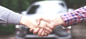 business men shaking hands after buying a car