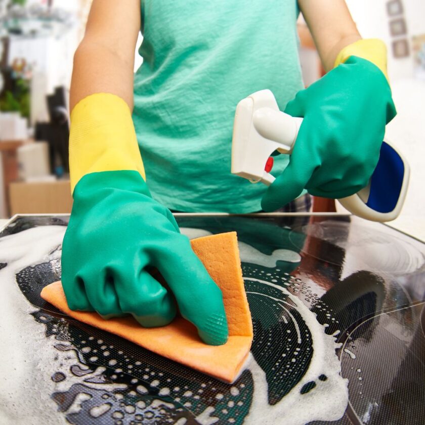 person cleaning a stove in a kitchen 