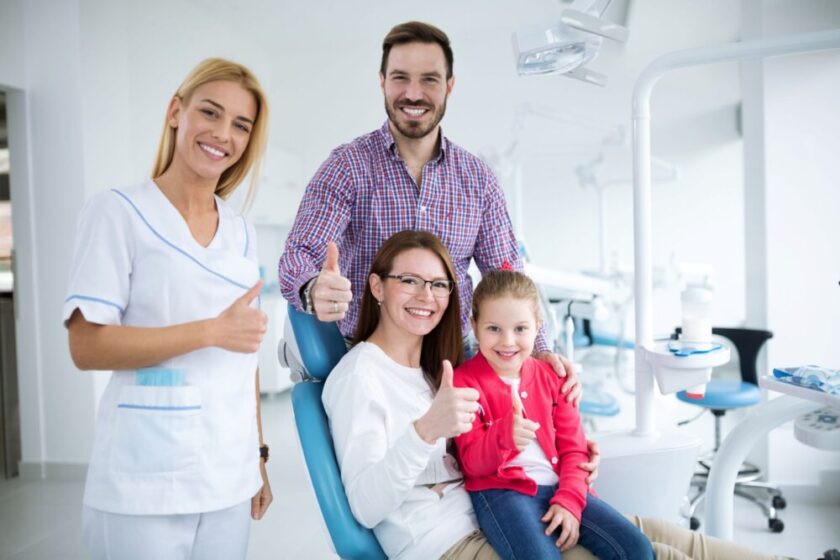 Family sitting in a dentist office giving a thumbs up