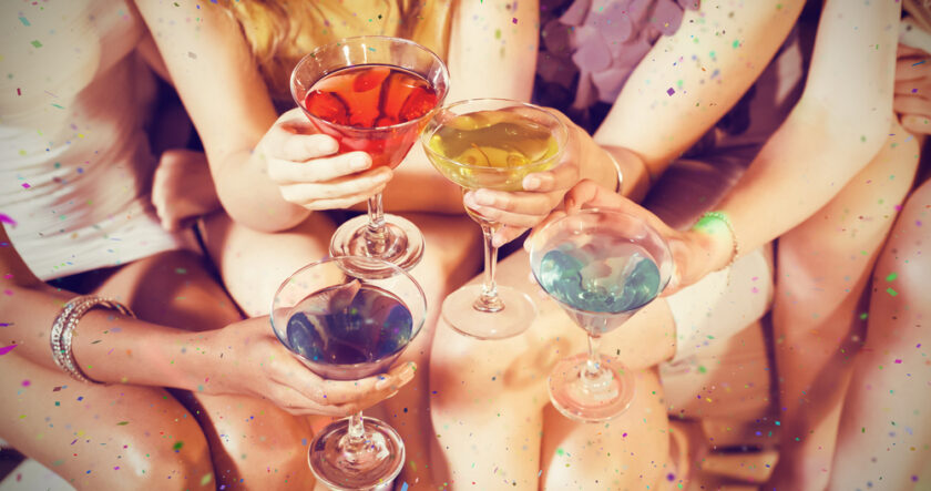 Girls with cocktails toasting against flying colours