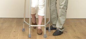 person using a walking aid with the help of another
