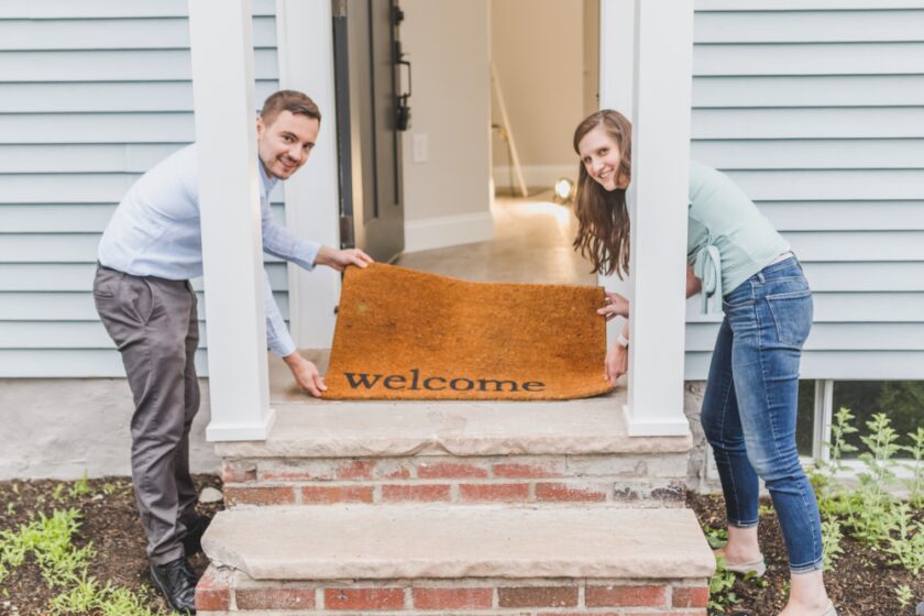 Couple holding a welcome door mat