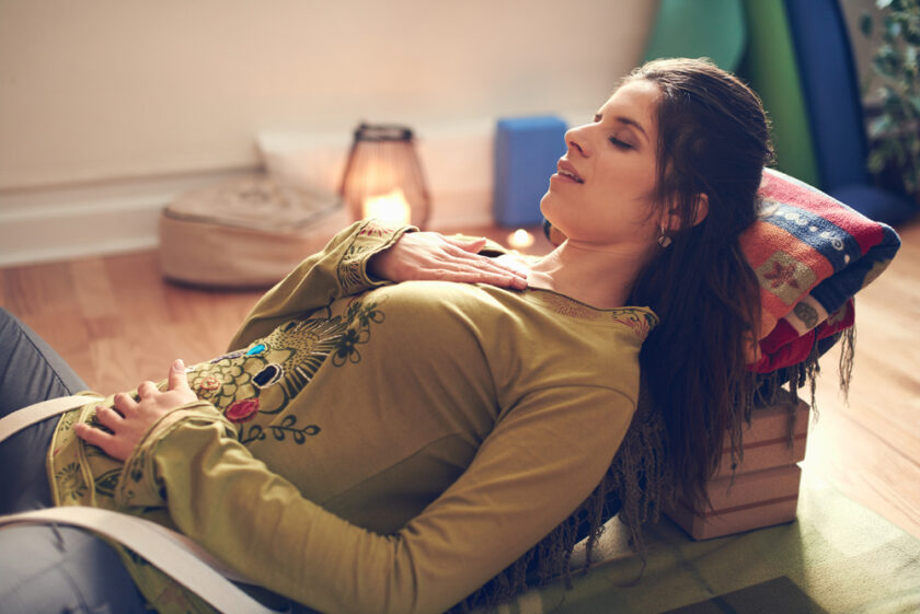 Serene lady relaxing and meditating on a yoga mat in a cosy house