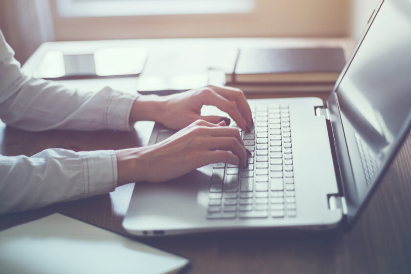 Woman working in home office hand on keyboard close up.