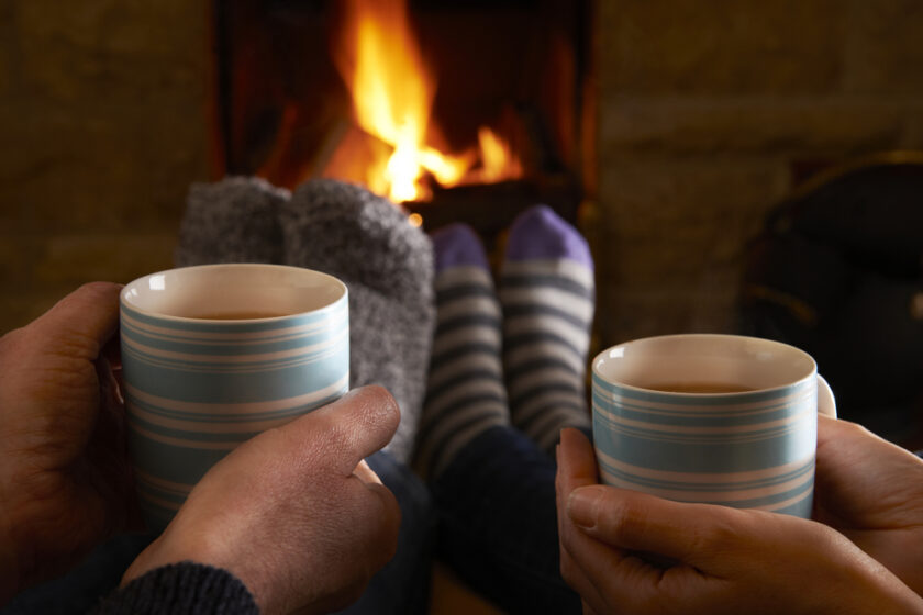 Couple With Hot Drink Relaxing By Fire
