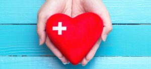 person holding a red heart with a cross on it
