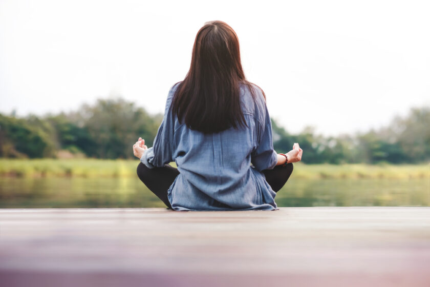 Young Woman Practices Yoga in Outdoor. Sitting in Lotus Position. Unplugged Life and Mental Health Concept. Sukhasana Posture and Meditating