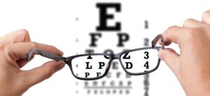 person holding glasses in front of an eye chart