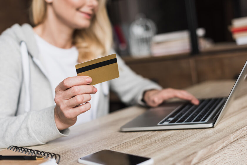Woman sat at a computer with her credit card online shopping