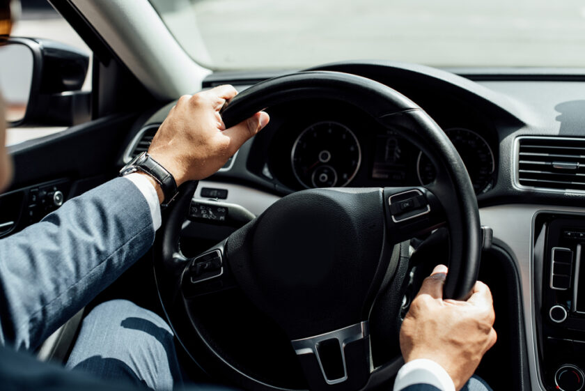 Man with his hands on a car steering wheel