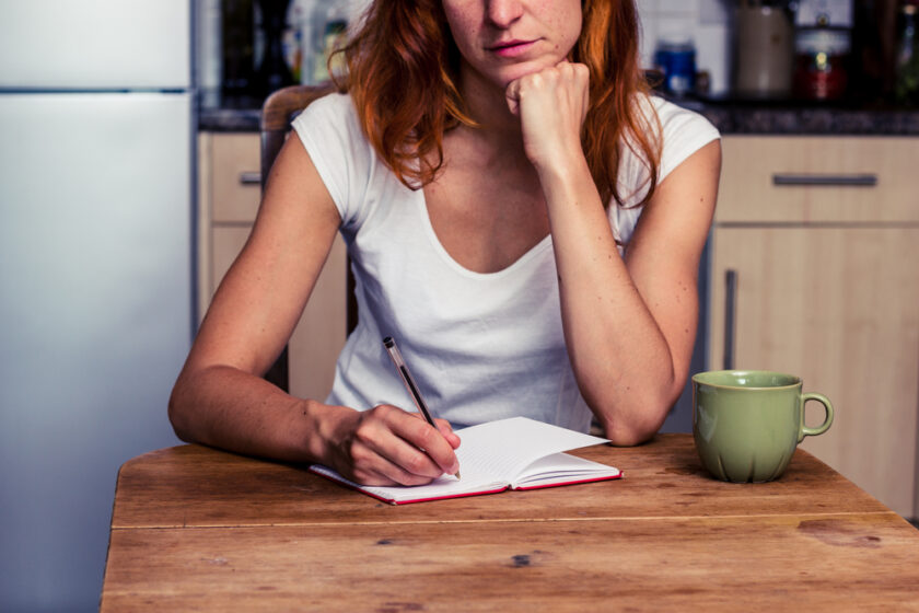 Woman makng a shopping list in her kitchen