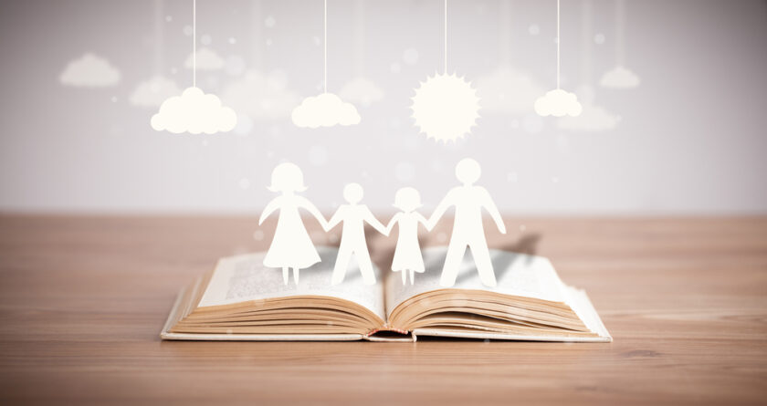 Cardboard figures of the family on opened book. The symbol of unity and happiness