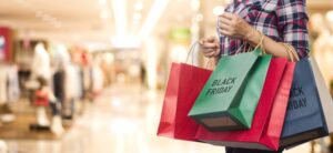 woman shopping in a mall holding lots of bags one which says black friday