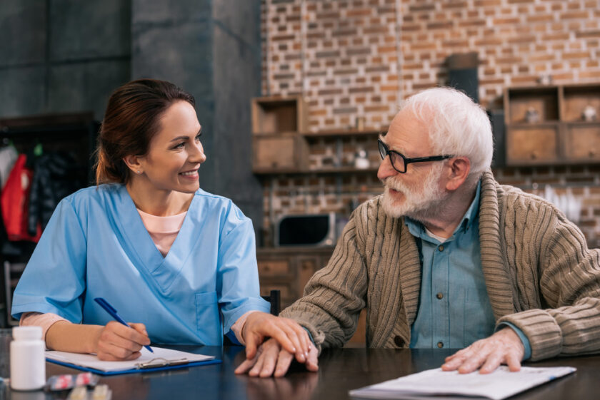 Older male talking with a younger female in scrubs