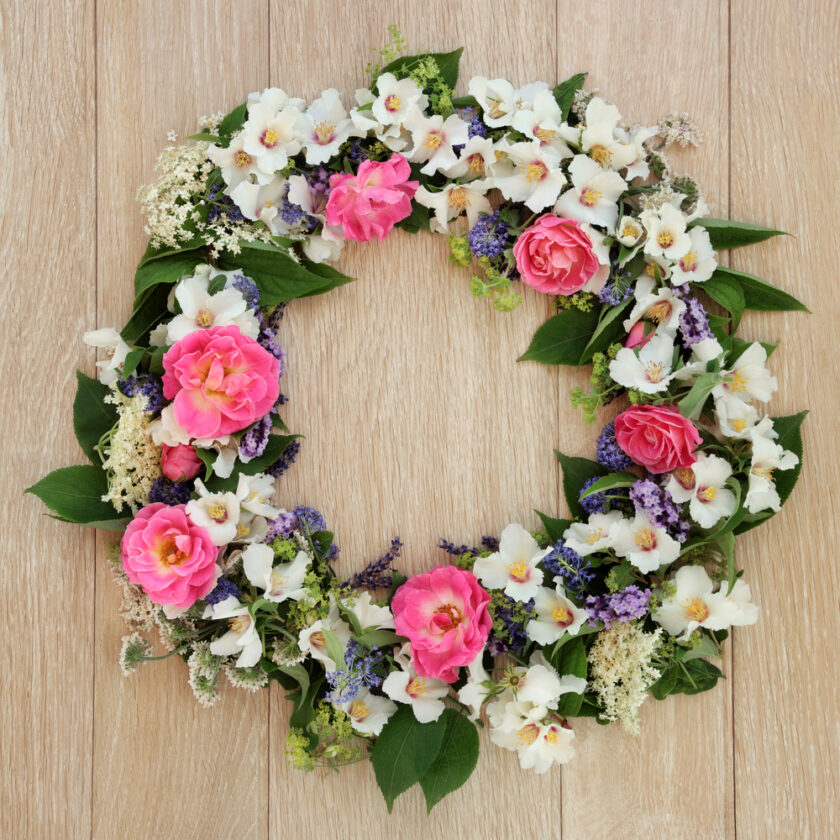 Summer flower wreath over light oak background.