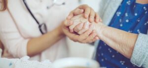 Social worker holding hands with older woman