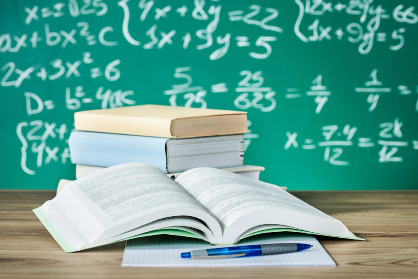 Books in front of a chalk board with maths on it