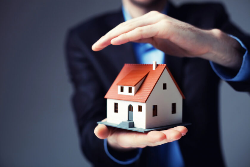 Person holding a mock up of a house protecting it