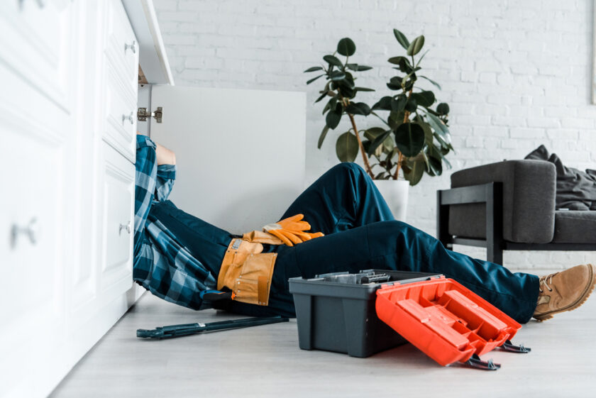 Man working on plumbing under a sink