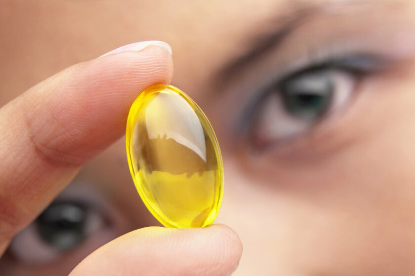 Woman looking at a vitamin tablet