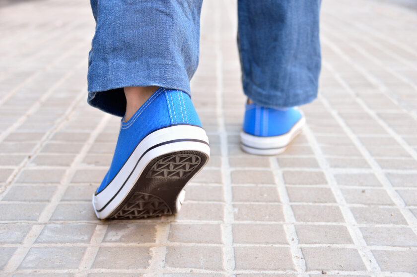Cropped rear view of a young with sneakers walking along a street