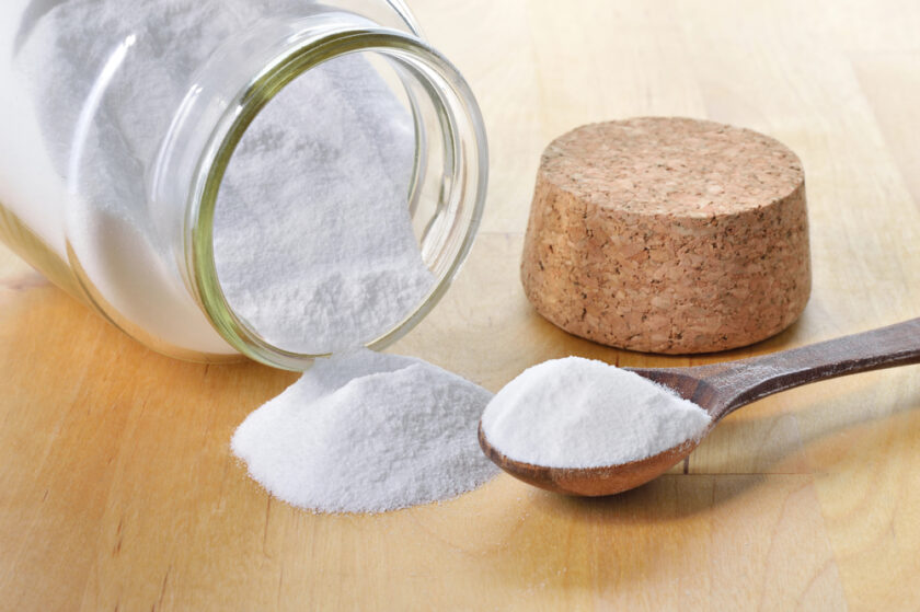 bicarbonate of soda in a glass jar tipped on a table and a spoon