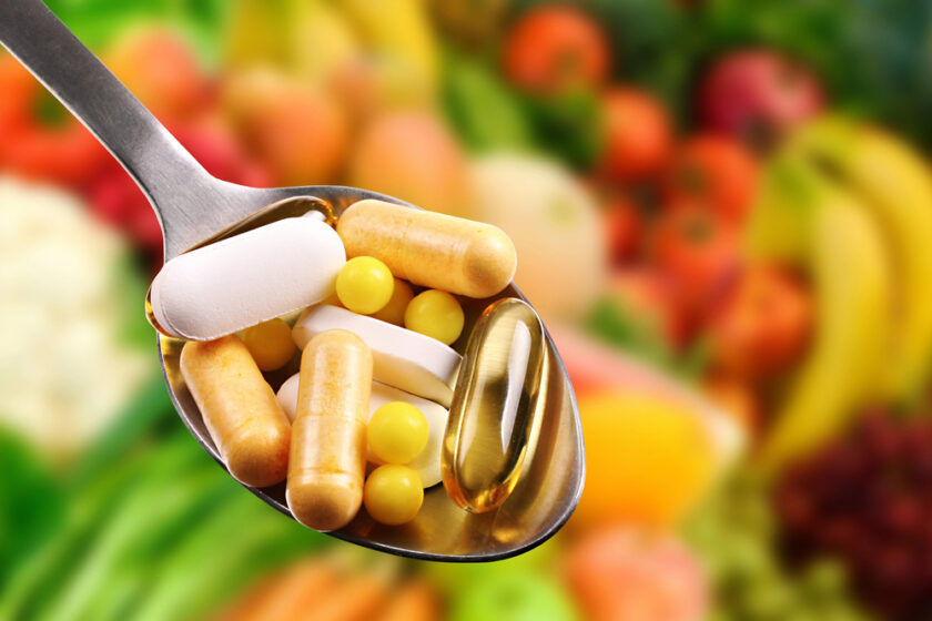 Spoon with dietary supplements on fruits background