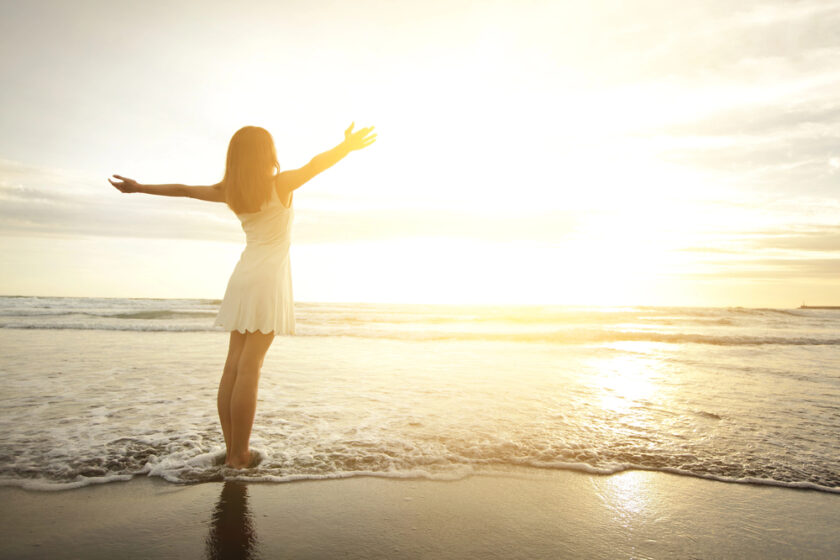woman by the sea with her arms out in joy