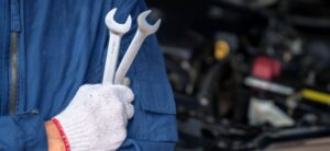 Man in a garage holding wrenches
