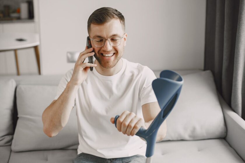 Man on a phone which holding a crutch