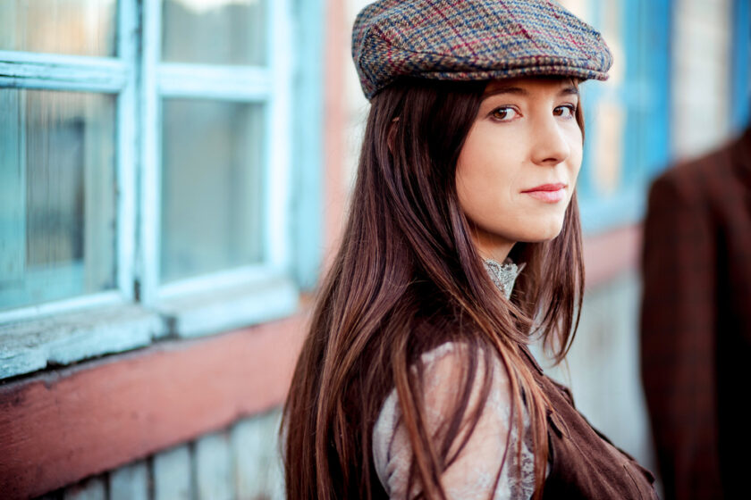 Young woman wearing tweed flat cap old fashioned portrait brown clothes, long hair.