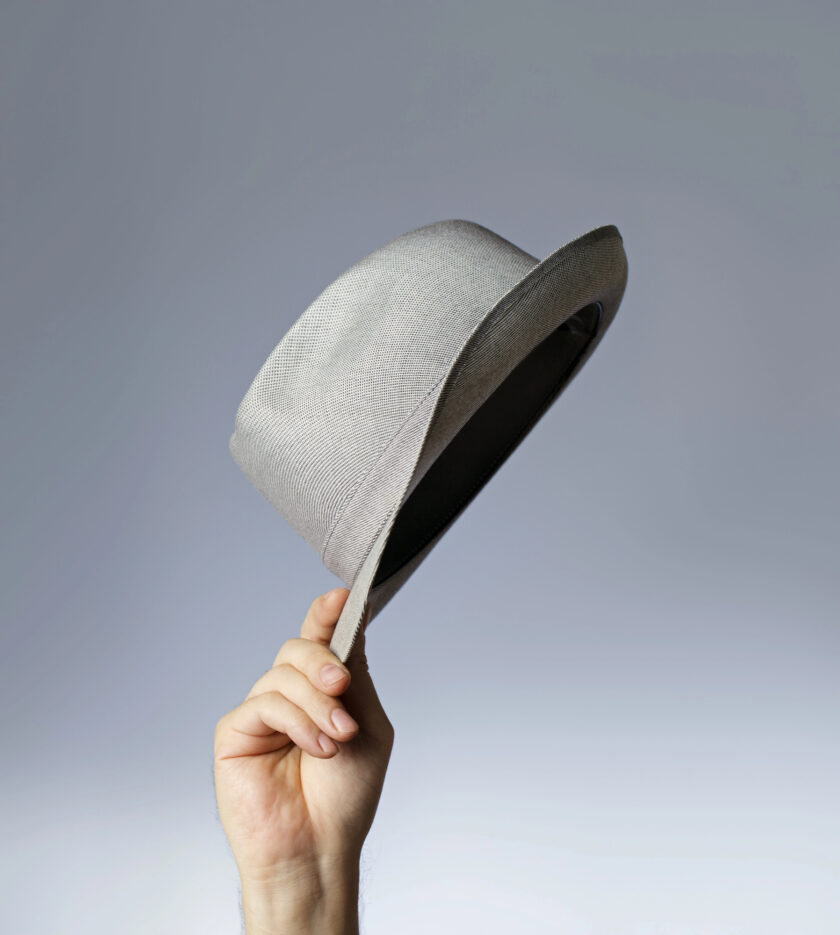 Person holding a trilby in the air