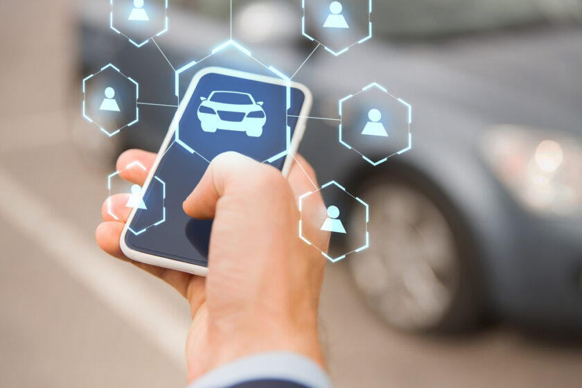 business, transportation and future technology concept - close up of businessman hand with smartphone and virtual car sharing icons