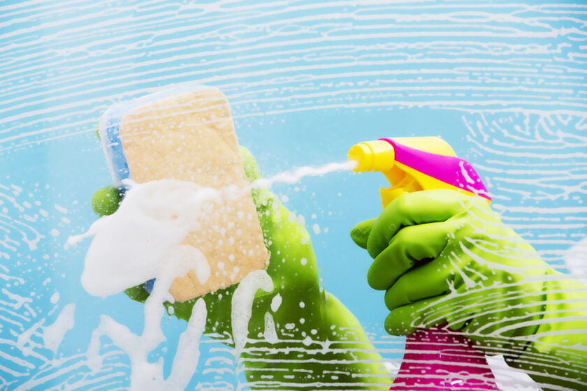 person spraying cleaning fluid on a sponge
