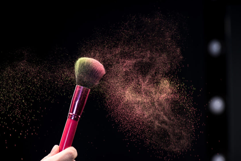 Make up powder on a brush against black background 
