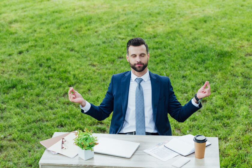Business man sat at a desk in a field