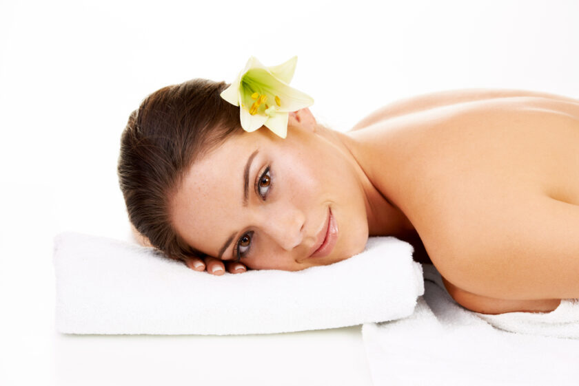 Happy woman, portrait and relax with flower in spa, zen or massage isolated on a white studio background. Face of female person or model smile in skincare for health body therapy, salon or treatment.