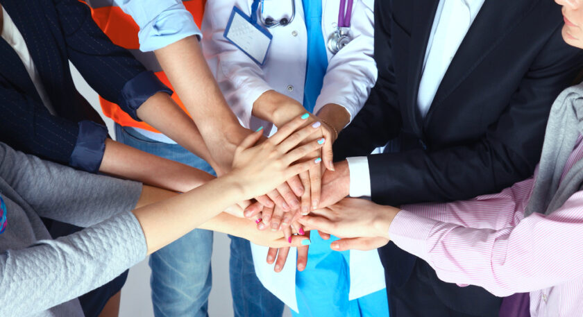 Portrait of people with various occupations putting their hands on top of each other.