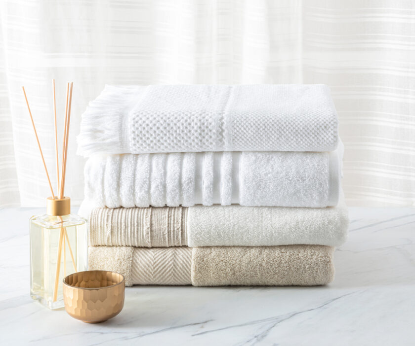 White cotton bath towels folded and aroma diffuser on a white marble table in the bathroom