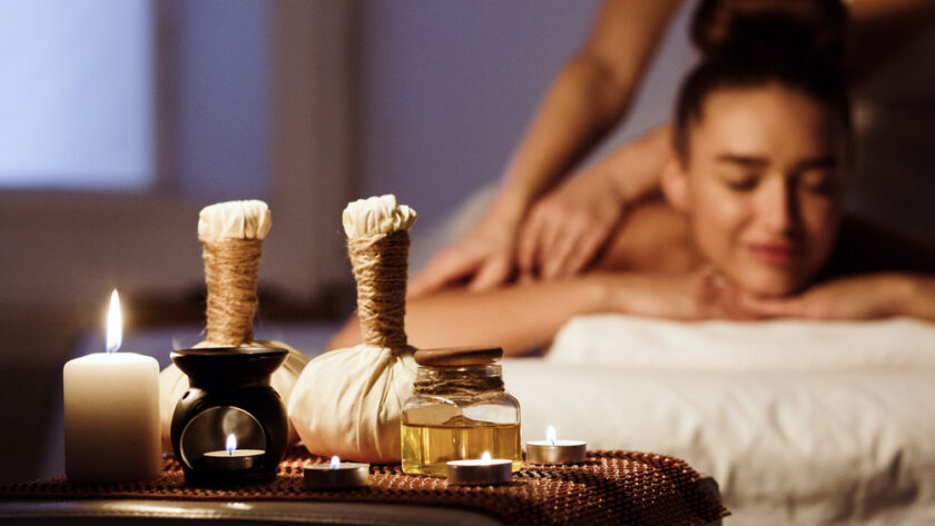 Herbal massage. Woman relaxing in spa salon with spa composition on foreground
