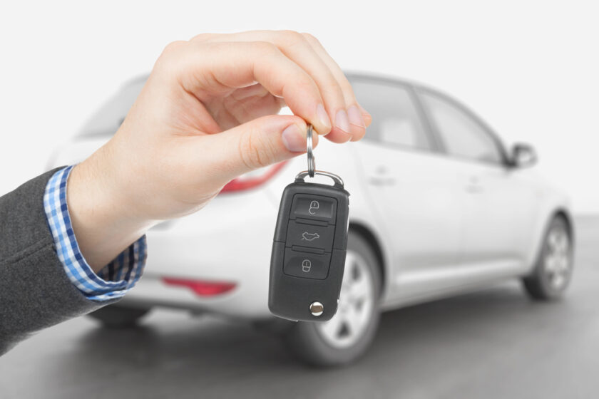 person holding a car key infront of a white car