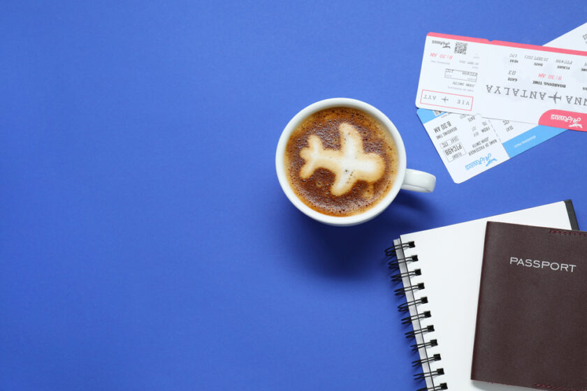 Flat lay composition with passport, cup of coffee and tickets on blue table, space for text. Business trip
