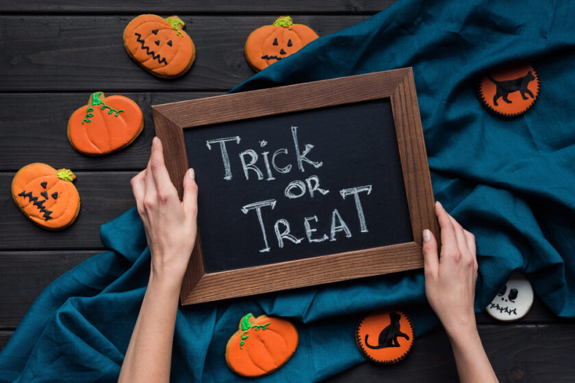 Trick or Treat written on a chalk board with pumpkins around it