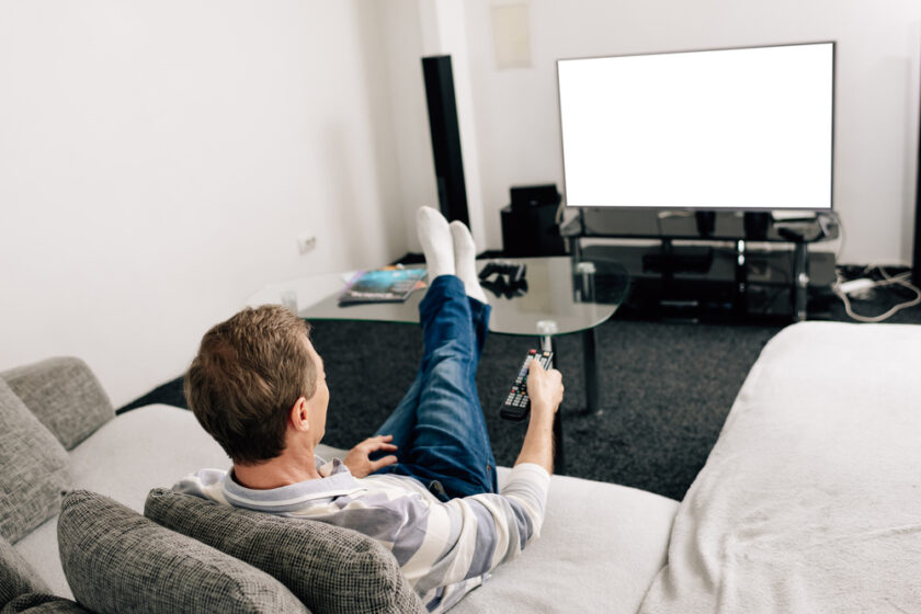 Person sitting watching the TV with remote in hand