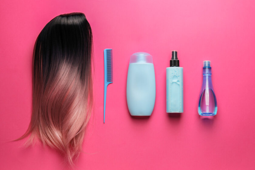 Unusual wig, comb and cosmetics for hair care on color background