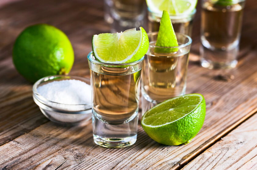Tequila sat out in glasses with a limes to the side and on top