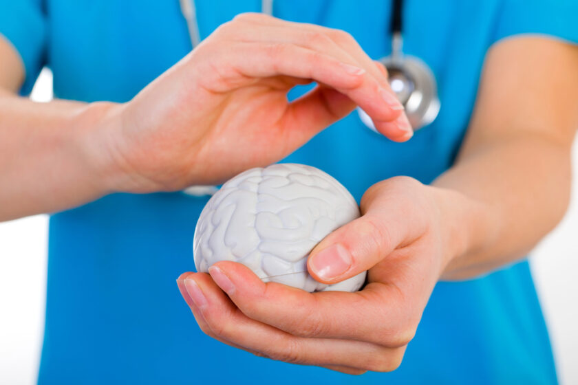 Nurse holding hands over a model of a brain