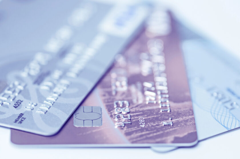 A close-up image of three overlapping credit cards with different designs, including chip technology. The cards are slightly out of focus, displaying various numbers and logos, but no personal details are clear. The image has a blue-toned filter.