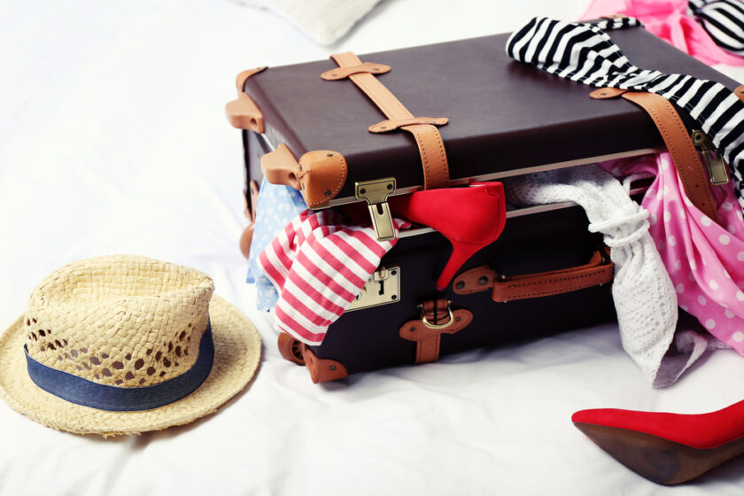 Suitcase with clothing on bed in room