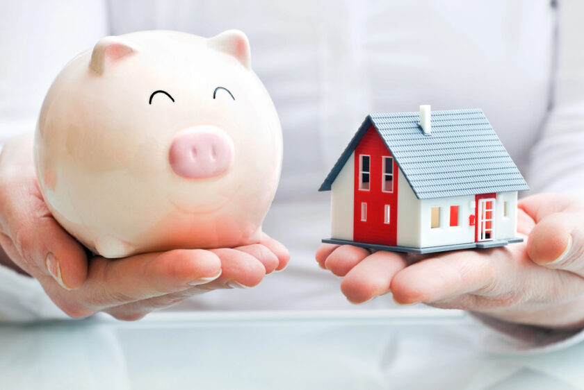 Person holding a piggy bank and a house